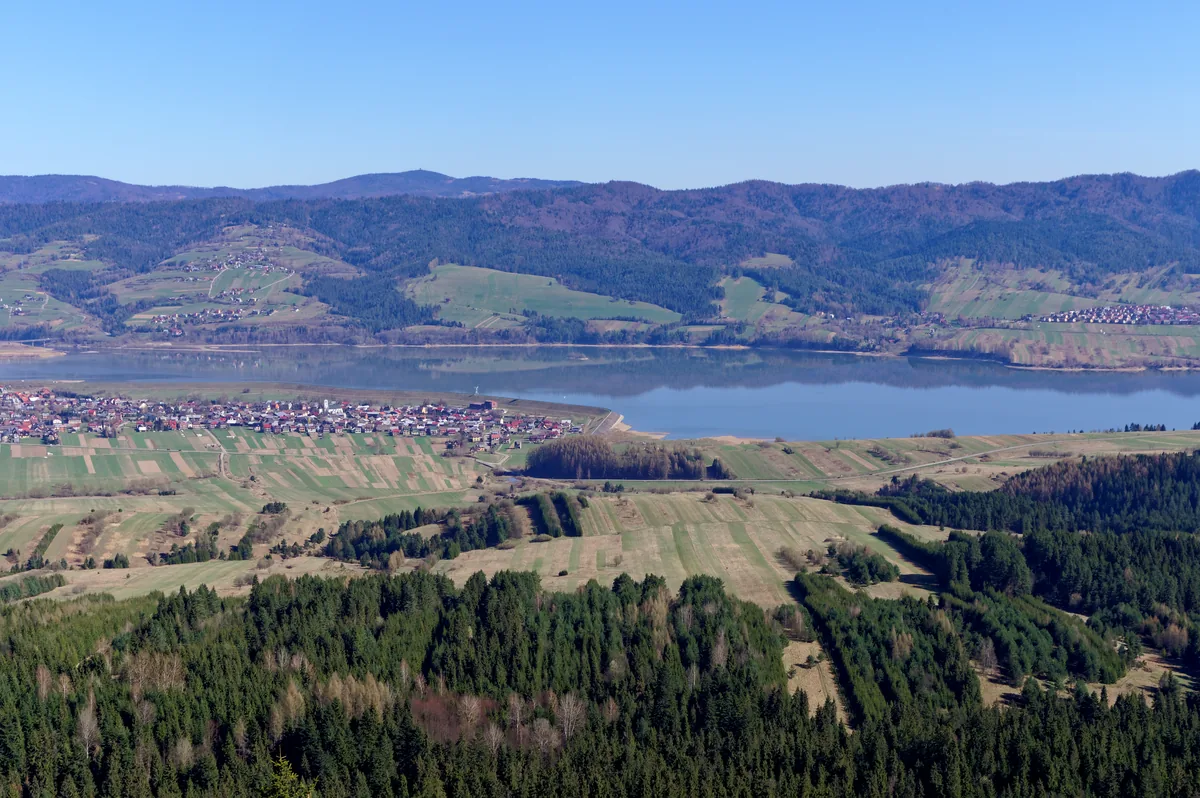Aerial view of Czorsztyn Lake reservoir surrounded by green hills and forest in the Pieniny mountains, Poland