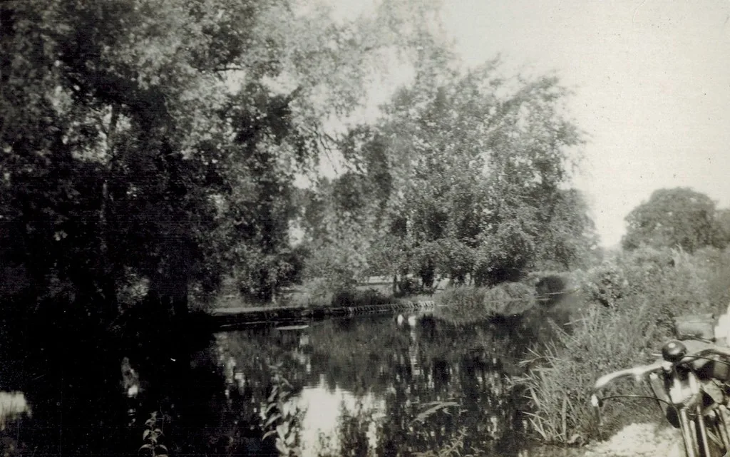 Vintage black-and-white photograph of the River Wylye, with overhanging trees reflected in still water.