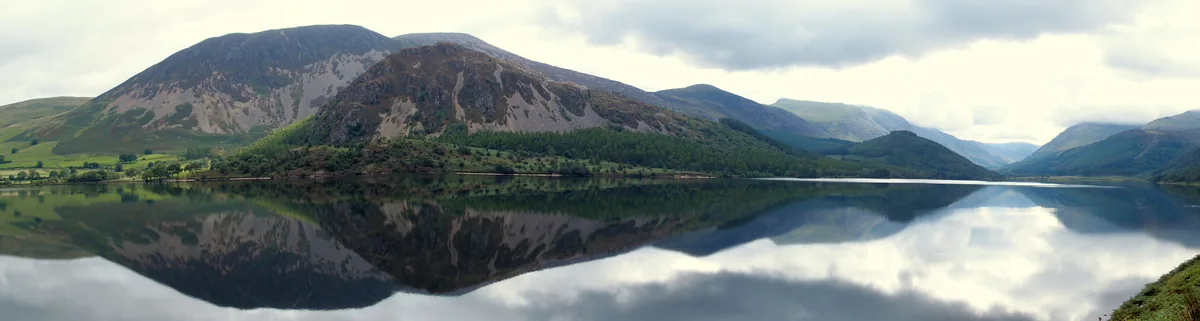 Panoramic view of Ennerdale Water lake with fells reflected in the still water