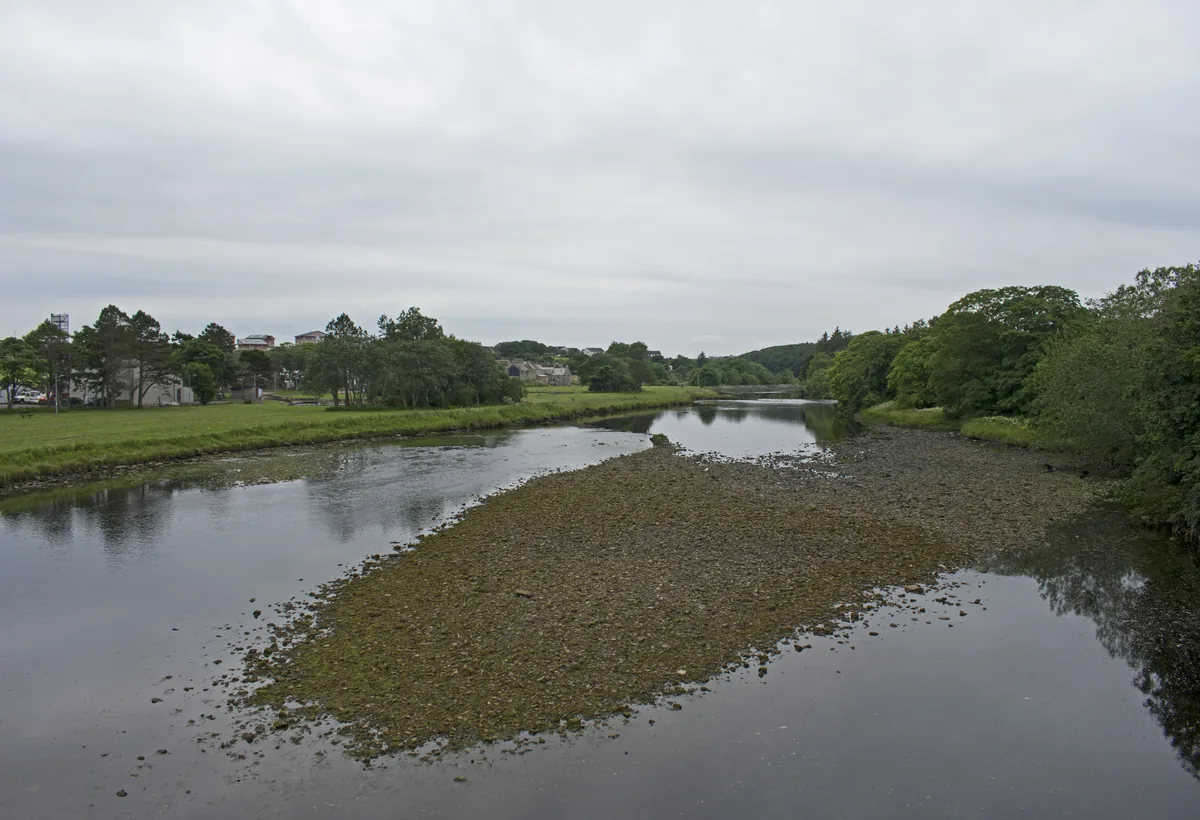 A view upstream along the River Thurso from Thurso Bridge in Caithness, Scotland, with open water and low countryside banks.
