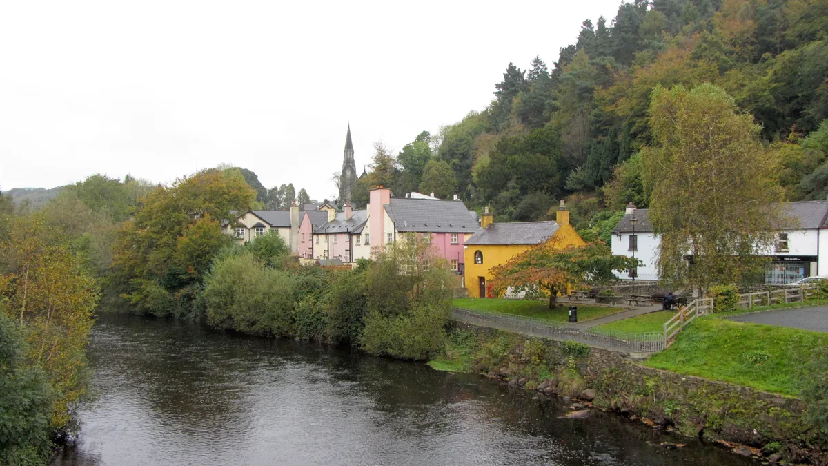 The Avoca River bending past colourful houses and a church spire in Avoca village, Co. Wicklow