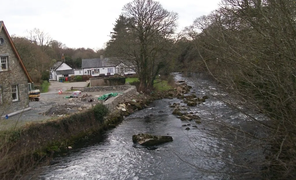The Afon Dwyfor river flowing below the bridge at Llanystumdwy, Gwynedd, Wales, lined with trees.