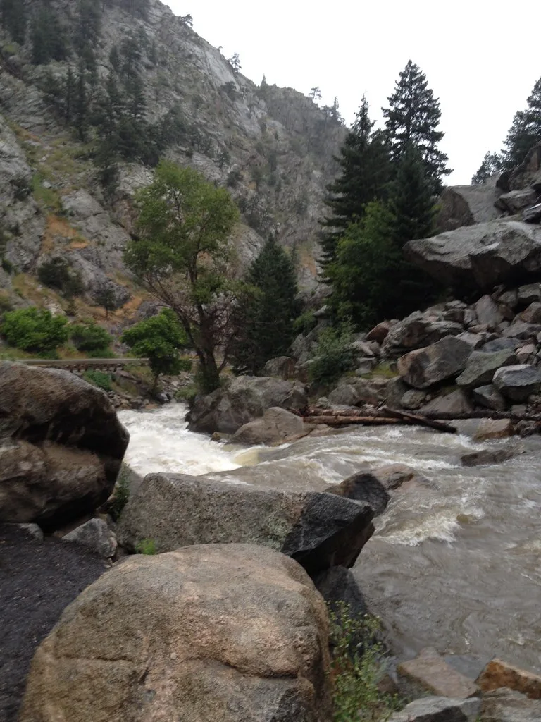 Boulder Creek flowing swiftly through a rocky canyon lined with pine trees and granite boulders in Boulder Canyon, Colorado.