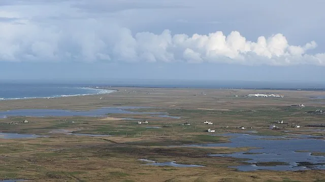 A shallow machair loch on South Uist with the sandy grassland machair landscape in the background.