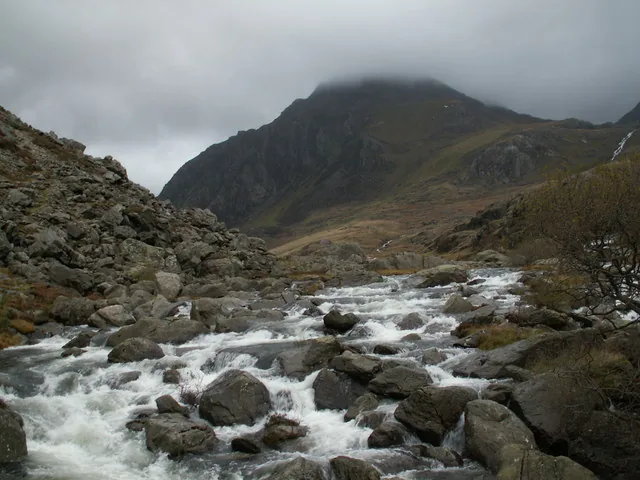 The Ogwen river flowing from Llyn Ogwen with the peak of Tryfan rising behind it.