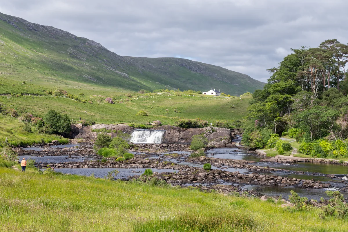 Aasleagh Falls cascading over rocks on the Erriff River with green hills in the background