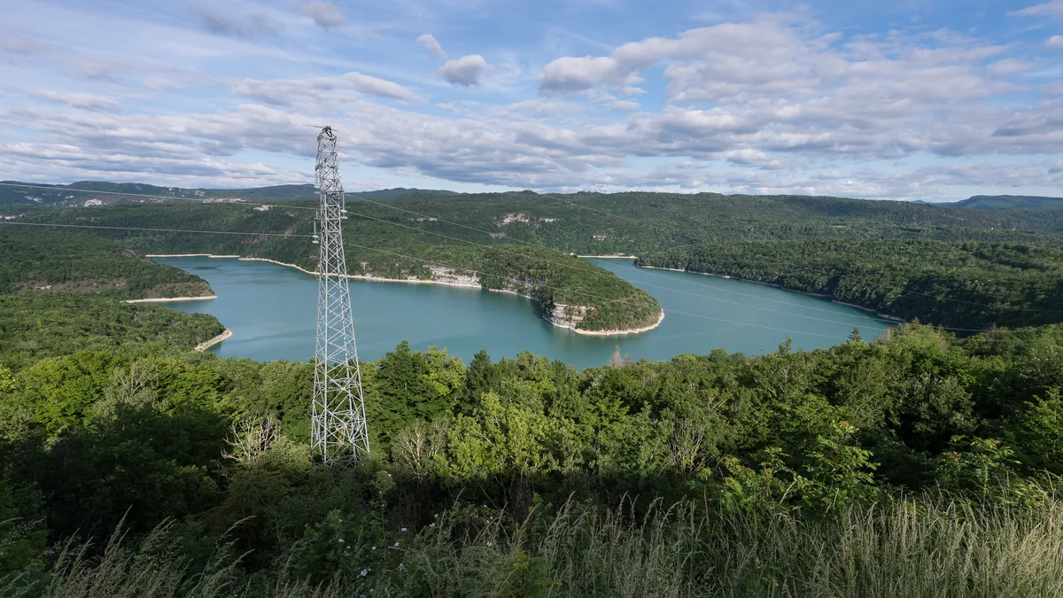 Turquoise waters of Lac de Vouglans winding through forested limestone hills, Jura, France