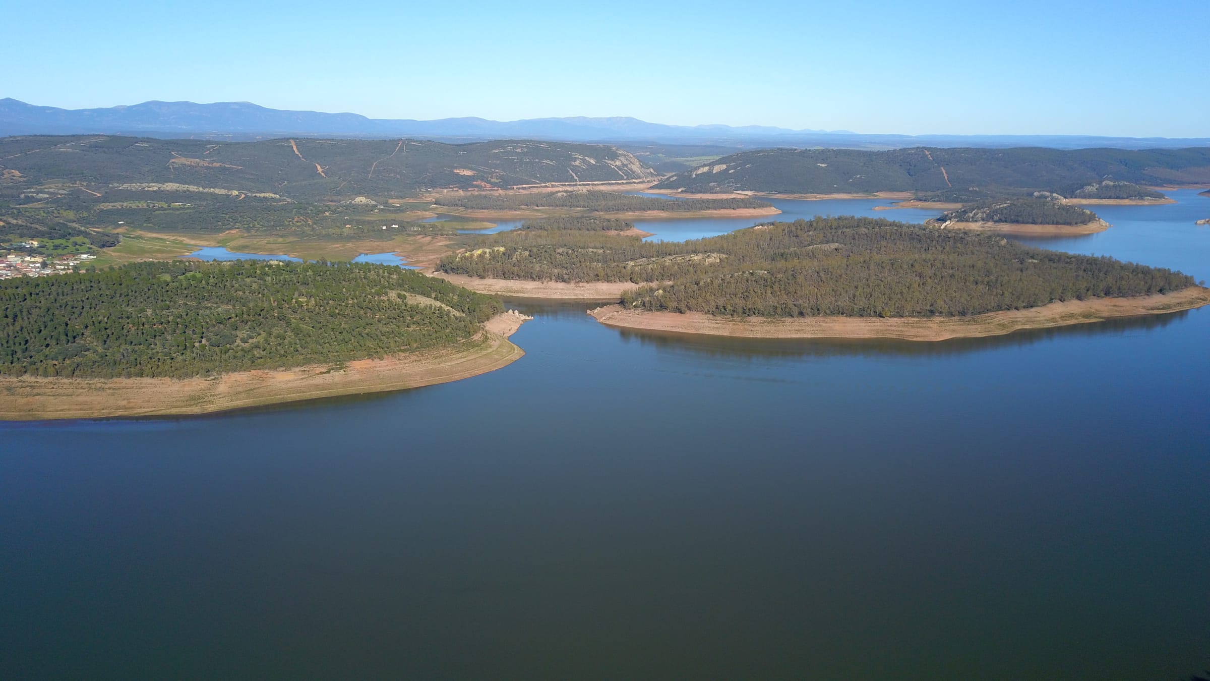 Drone view of Cíjara reservoir showing open water and the oak and cork dehesa hillsides of Extremadura.