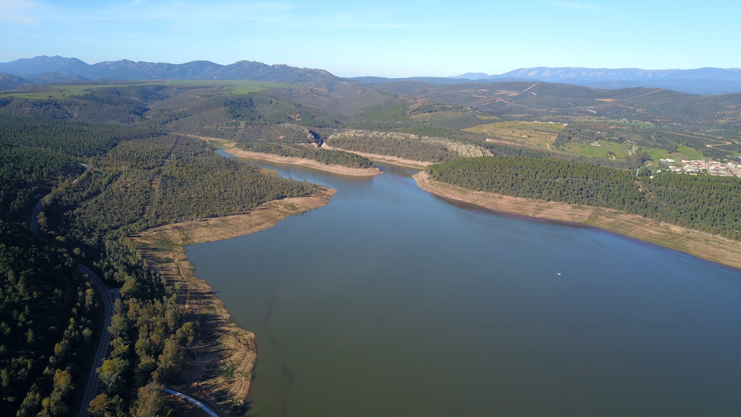 Low-altitude drone photograph over the surface of Cíjara reservoir, open water and wooded banks.