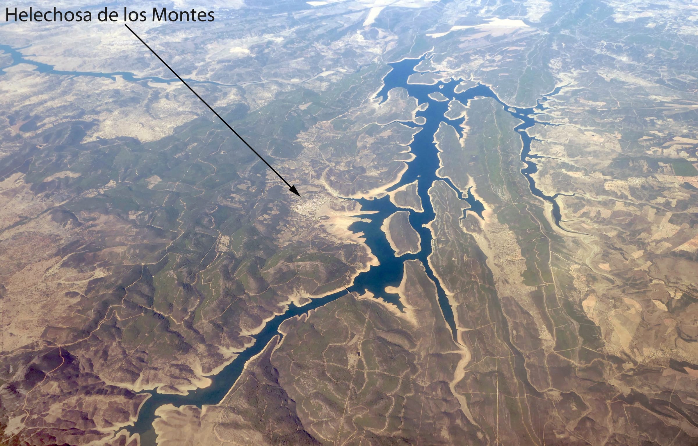 Aerial view of Cíjara reservoir with Helechosa de los Montes on the wooded shoreline.