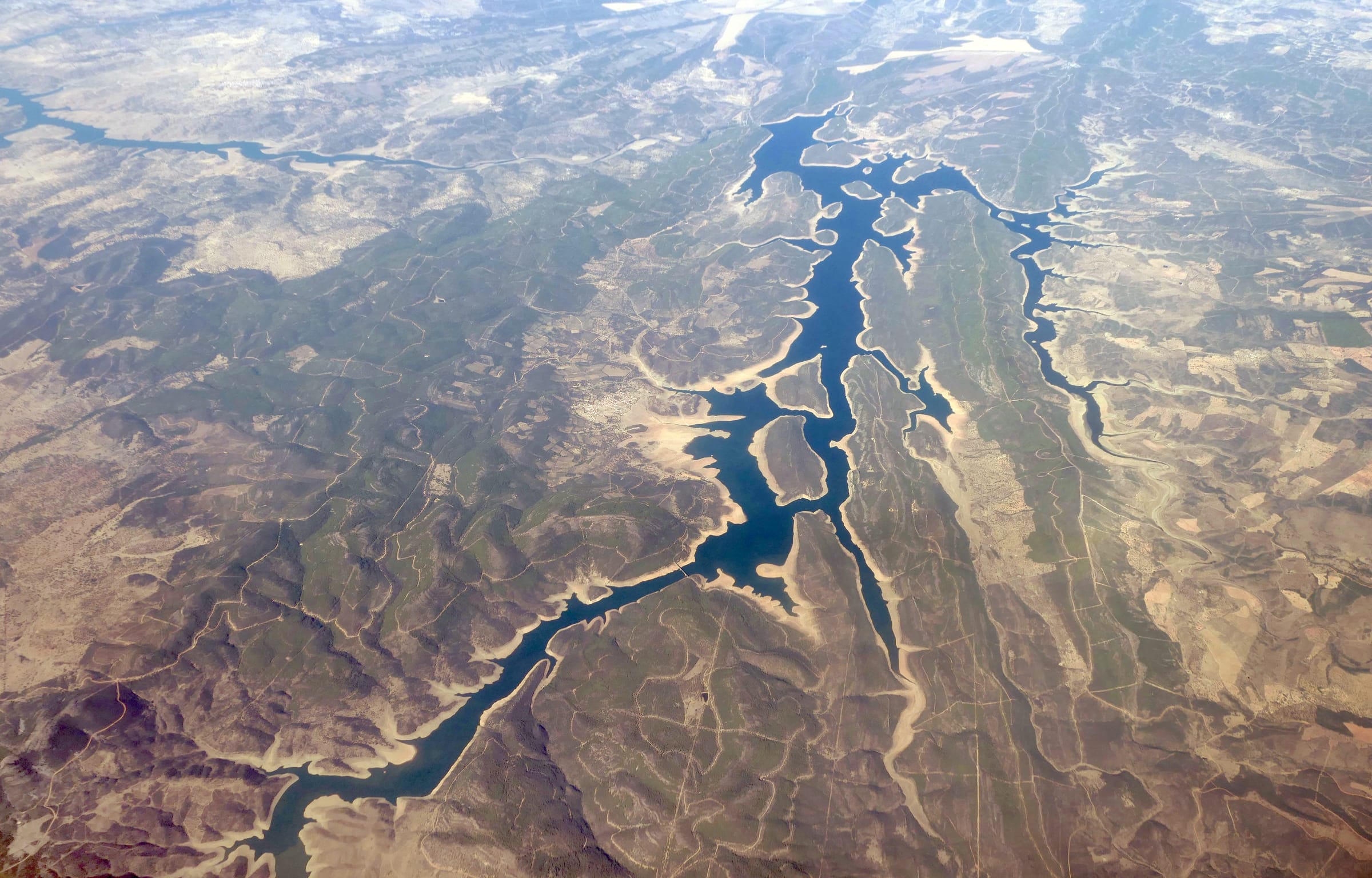 Aerial view across the full expanse of Cíjara reservoir, Extremadura, open blue water and dehesa hills.