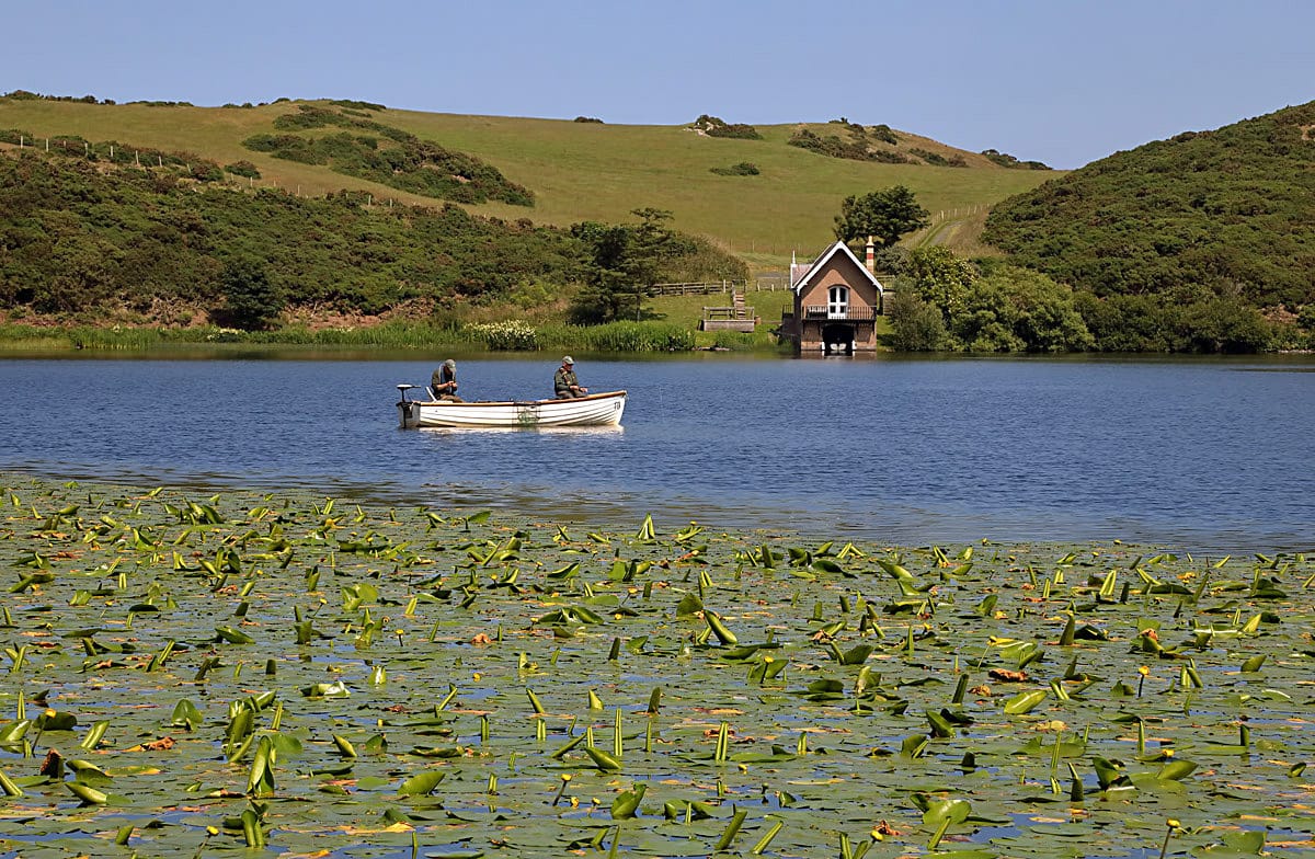 Angler fishing at Coldingham Loch with the lochside cottage and boathouse in the background.