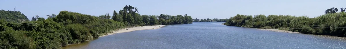 A wide panoramic view of the Karamea River from the State Highway 67 bridge near Karamea, West Coast, New Zealand