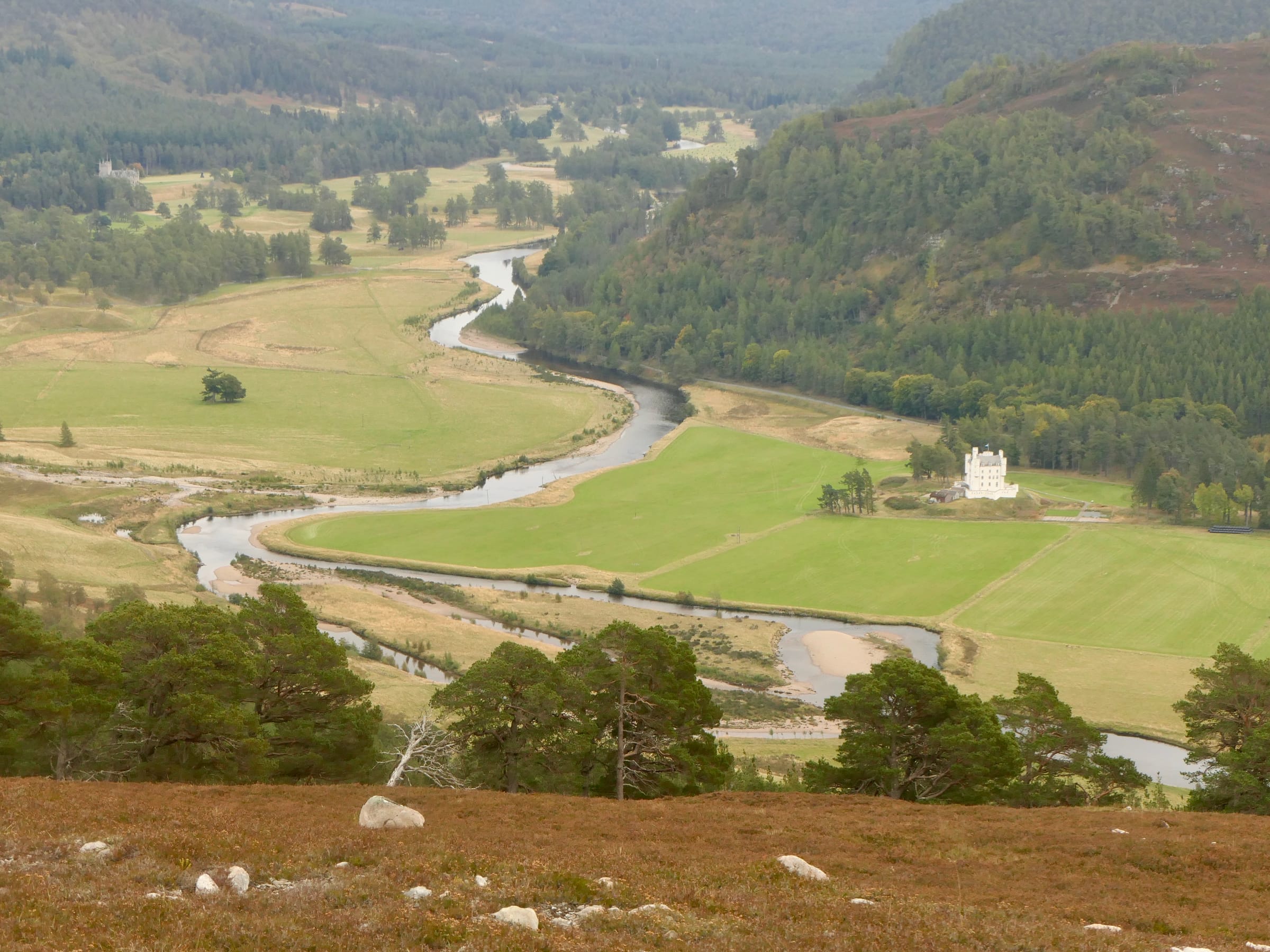 The River Dee running downstream from Braemar through a broad braided channel in the upper Cairngorms valley.