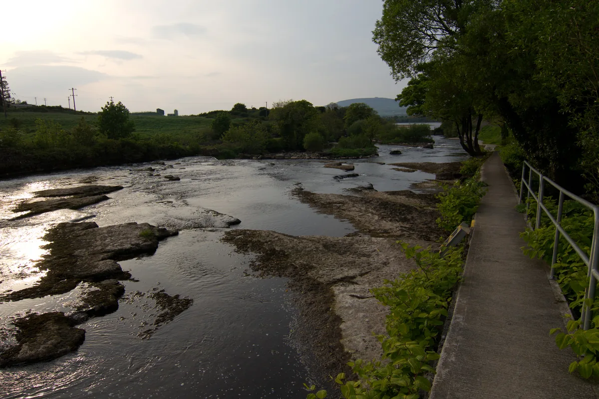 The Ballisodare River flowing over a broad limestone riverbed with a riverside path, Co. Sligo, Ireland