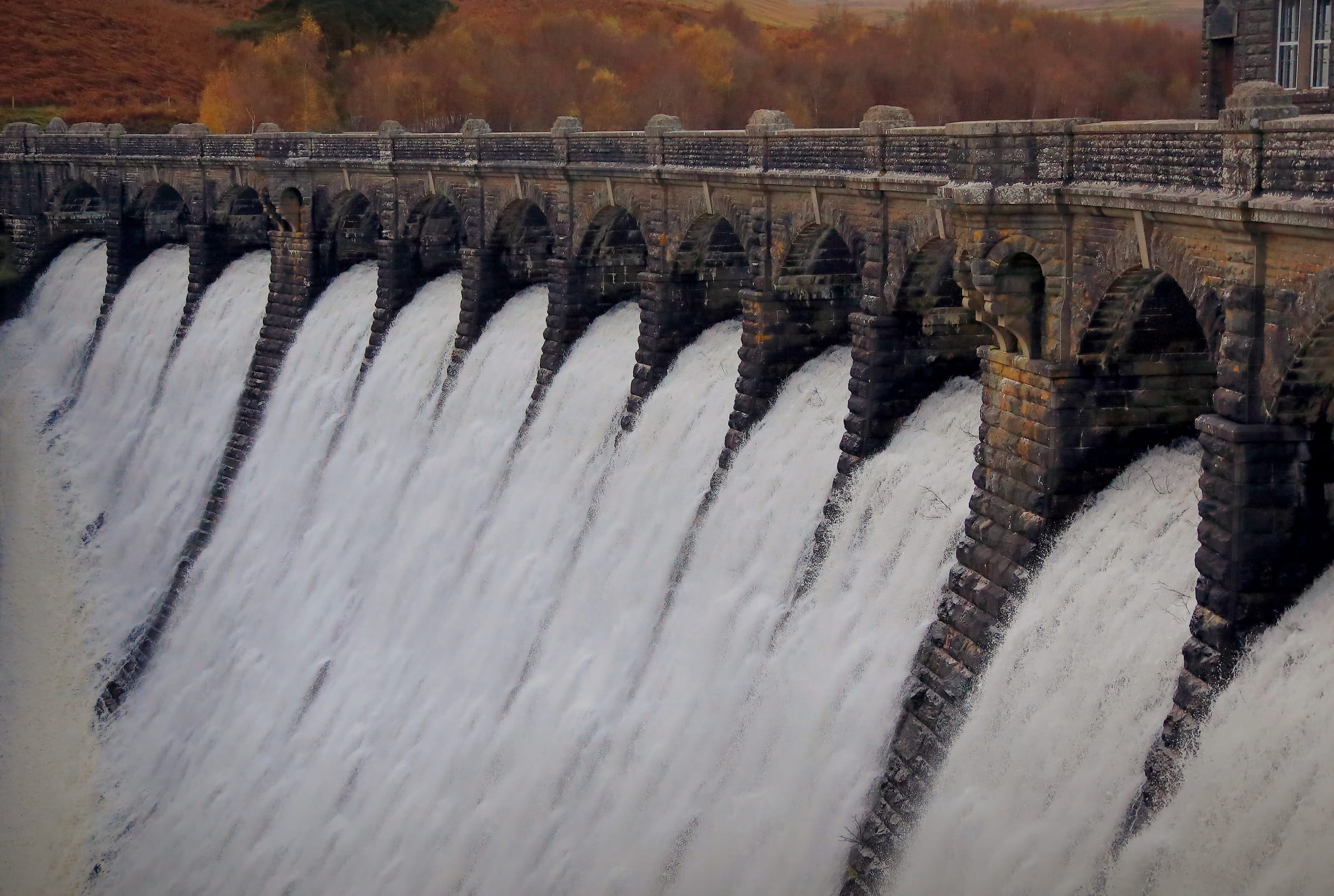 Craig Goch Dam with water cascading over its Victorian arched spillway in flood conditions, Elan Valley.