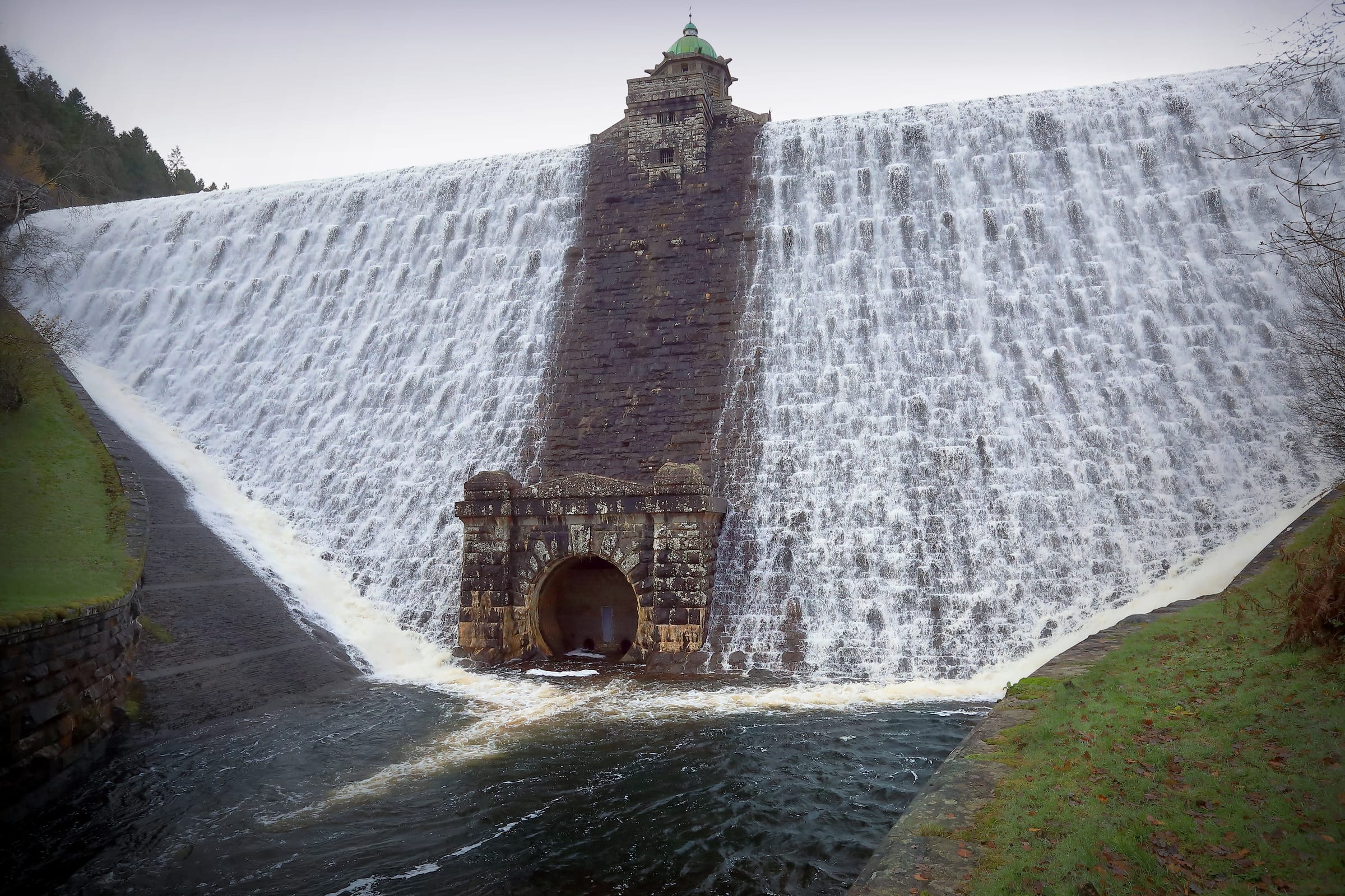 Pen y Garreg Dam overflowing, water sheeting over the full width of the Victorian masonry weir.