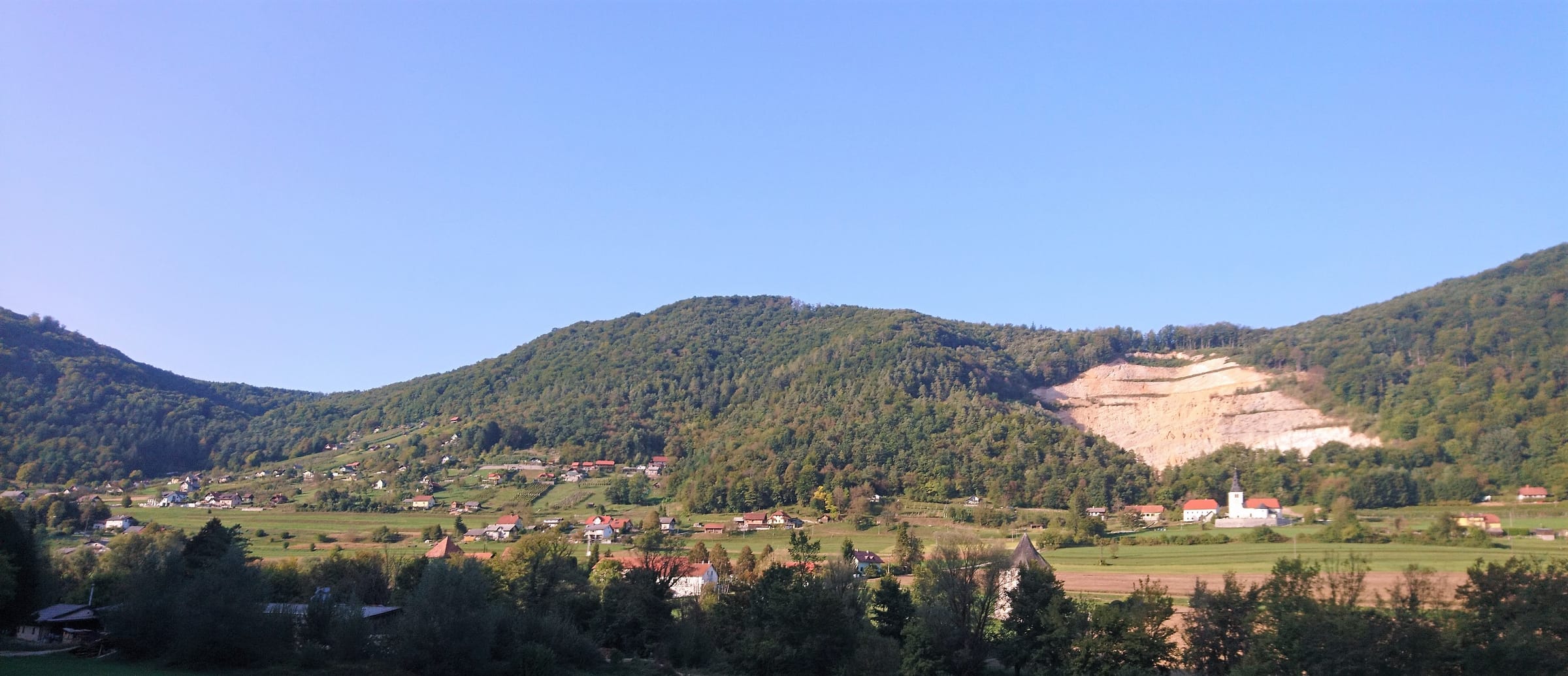 Panoramic view of the Krka at Soteska, Dolenjska, with wooded valley sides and the river reflecting sky.