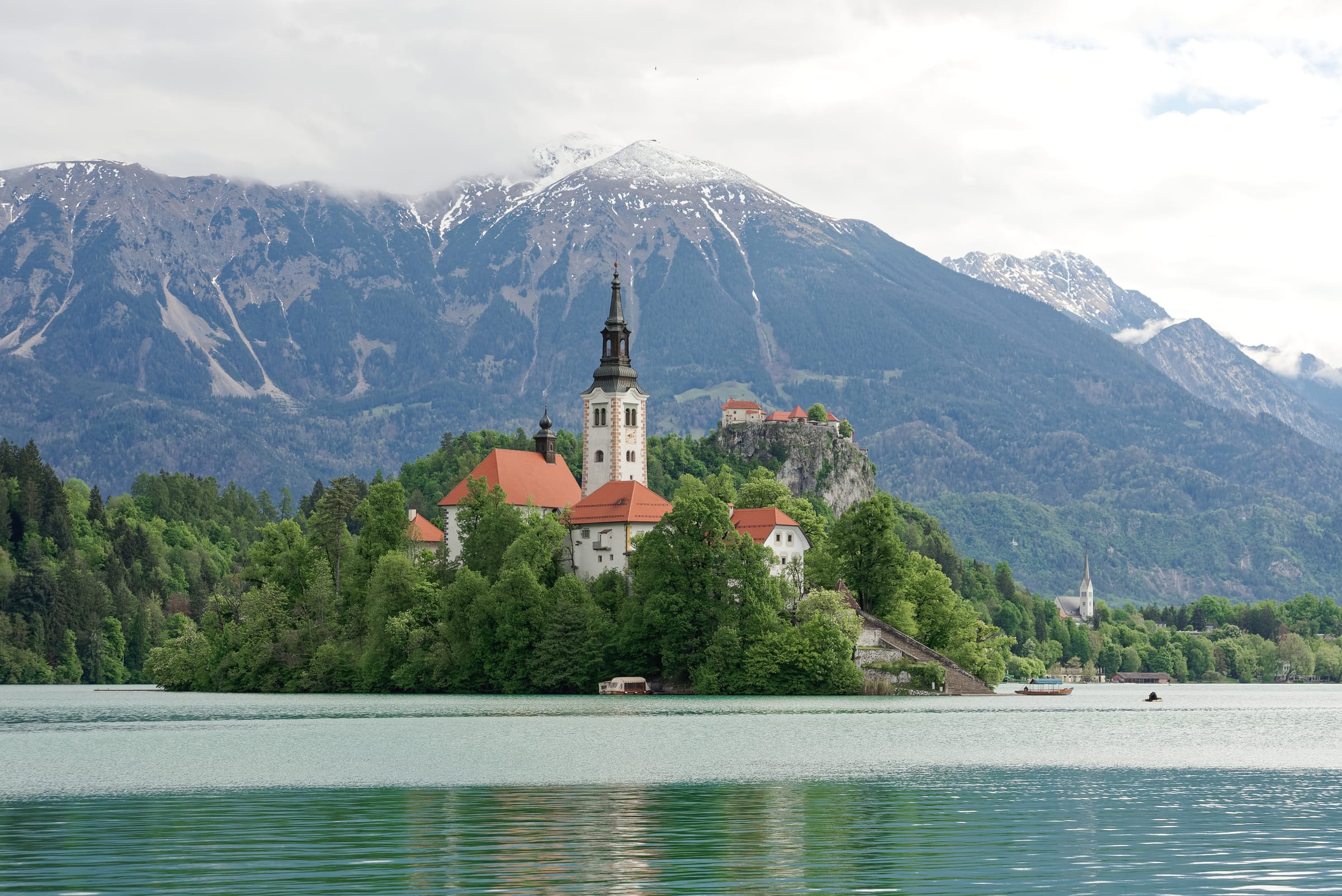 Lake Bled with the island and its church surrounded by open water, Bled Castle on the cliff, Alps behind.