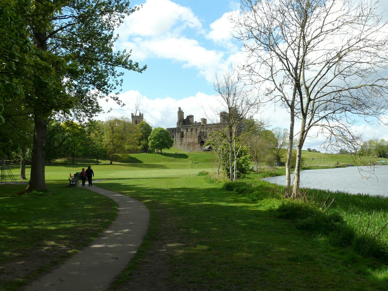 Linlithgow Palace viewed across the loch with open water in the foreground and the palace ruins on the far shore.