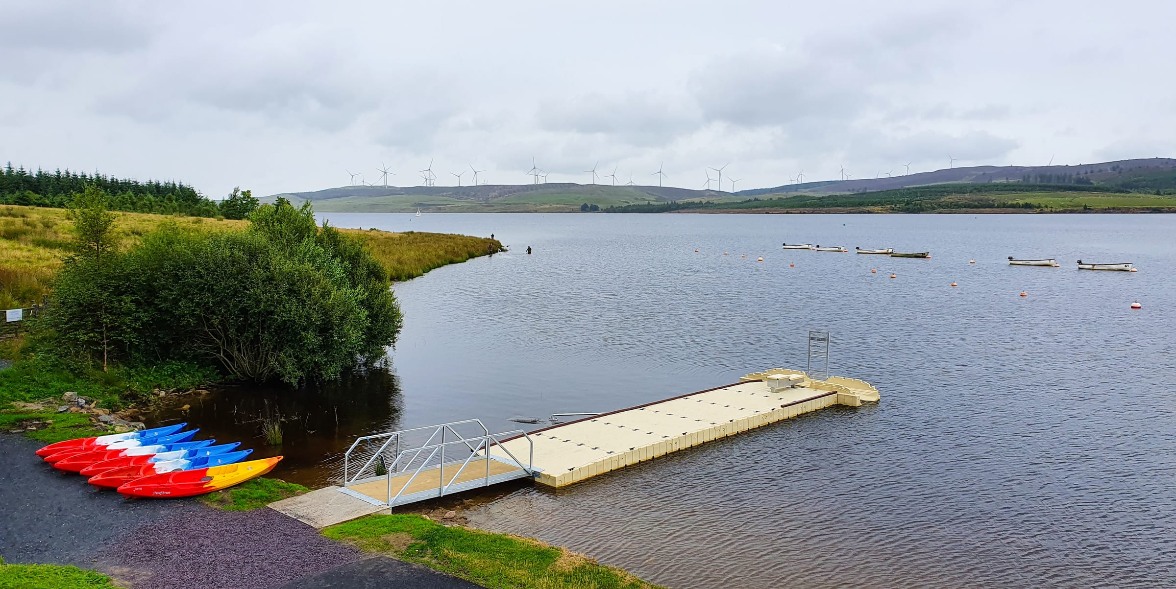 Wide panoramic view of Llyn Brenig reservoir showing the full breadth of open water under a cloudy sky.