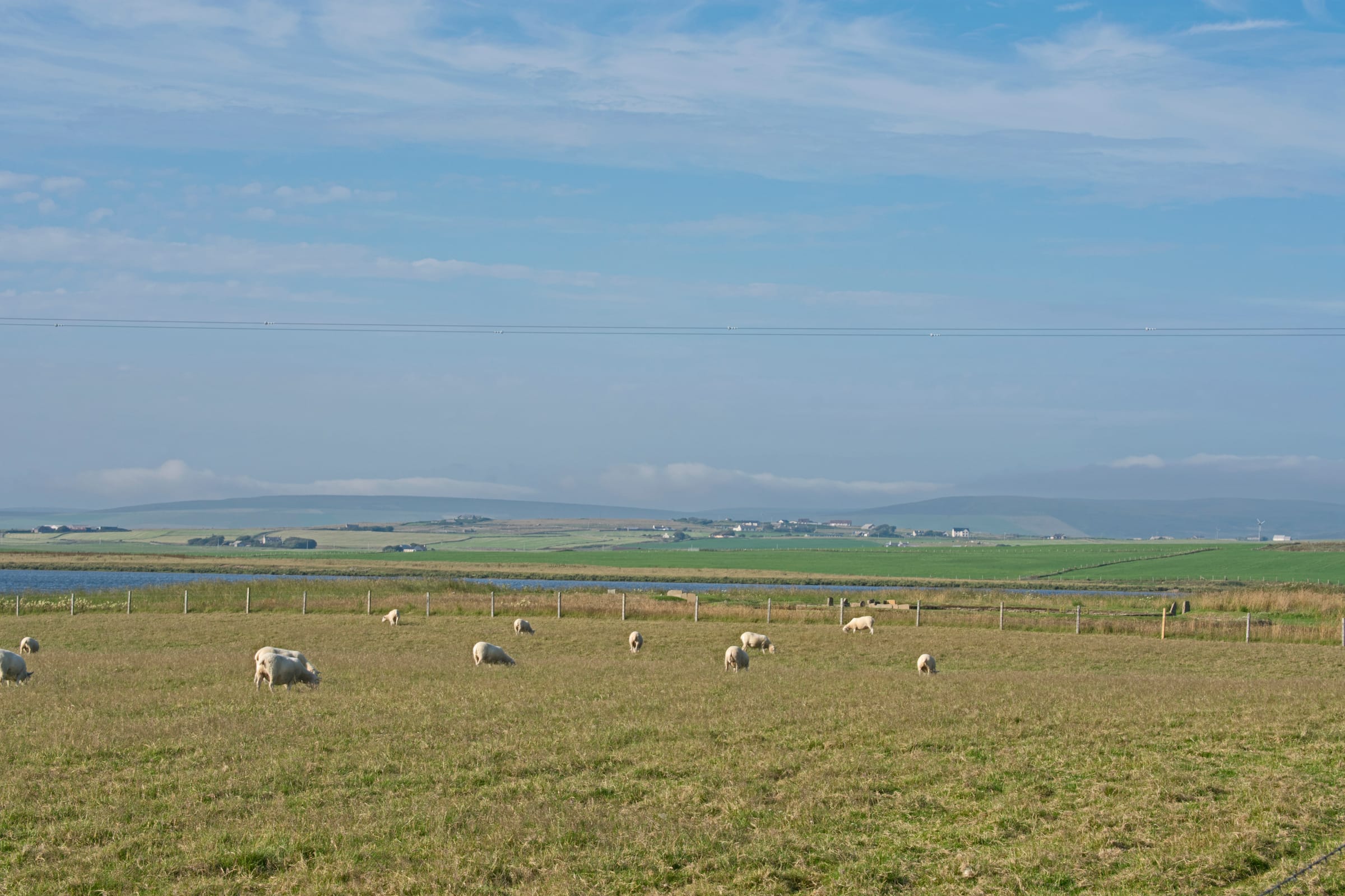 Loch of Harray stretching into the distance seen from the Standing Stones of Stenness, megaliths in the foreground.