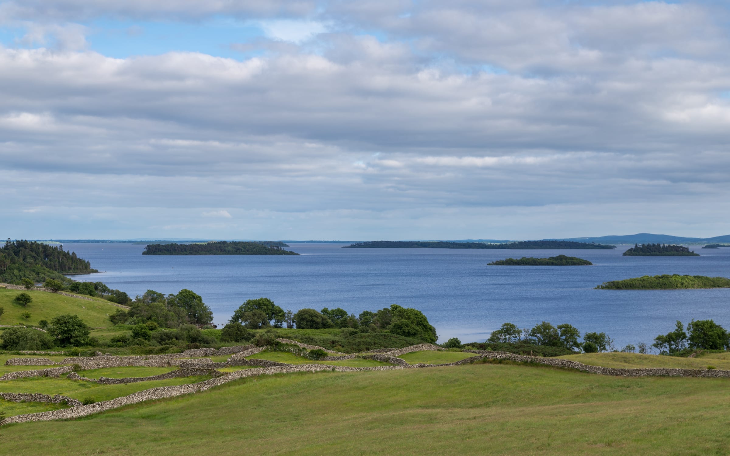 Broad view of Lough Corrib near Clonbur, open lake water with stone walls and green countryside.