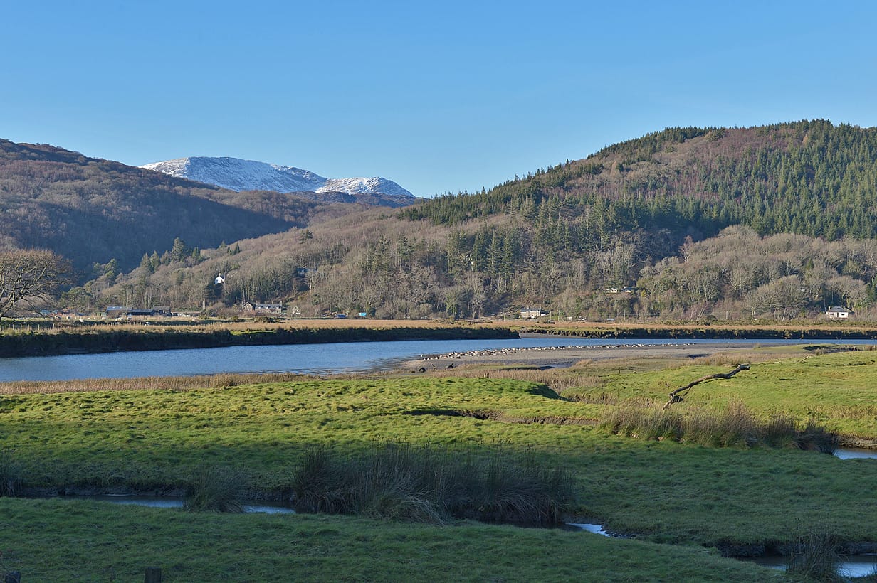 The Mawddach above Penmaenpool in winter light, a wide flat glide with wooded valley sides rising steeply.