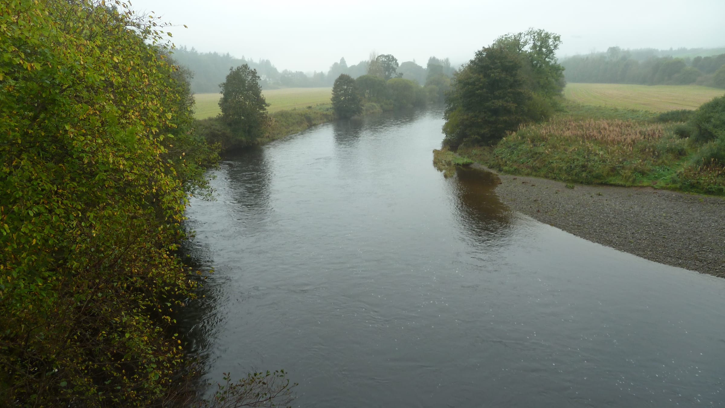 Looking upstream along the River Nith from Auldgirth Bridge in October, autumn foliage reflected in the slow pool.