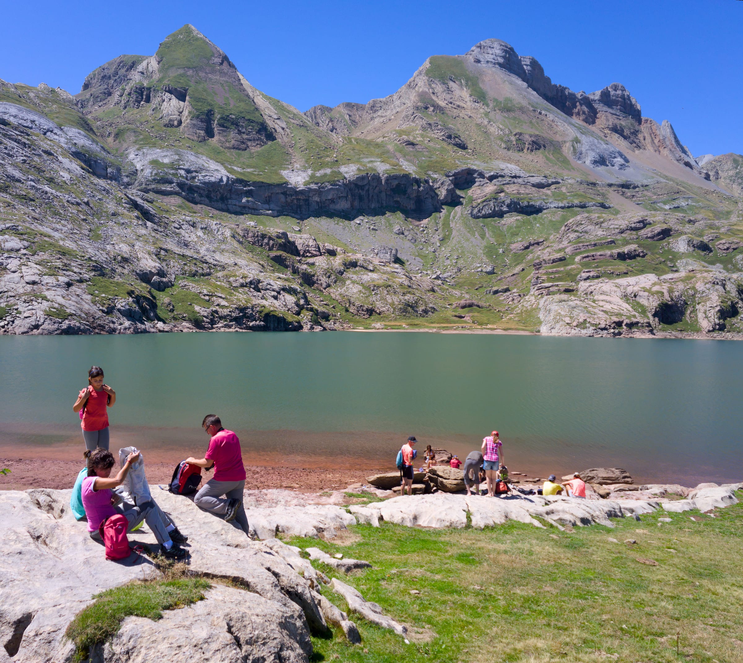 The blue glacial waters of Ibón de Estanés in the Aragonese Pyrenees on a clear summer day.