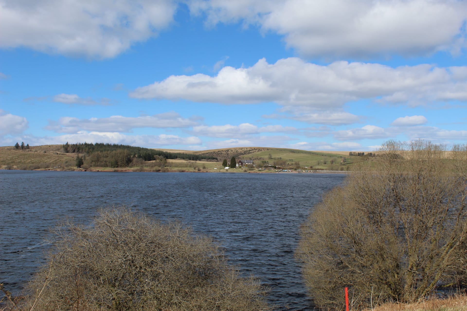 A broad view across the open water of Usk Reservoir with surrounding moorland and conifer plantations.
